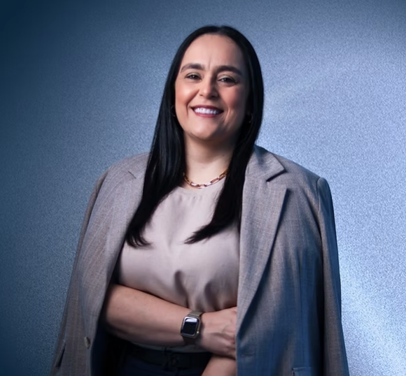 Patrícia Bastos sorrindo em seu ambiente de trabalho